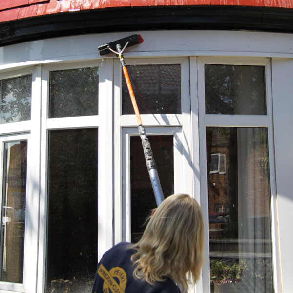 Pole and brush being used to clean facias of bay window.