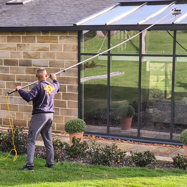 Using a long reach pole to clean the roof of a conservatory.